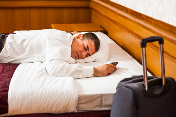 Tired businessman is sleeping on bed in hotel room