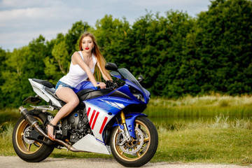 beautiful young woman with a motorcycle speed in nature