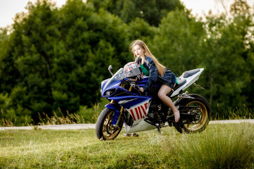 Plakat beautiful young woman with a motorcycle speed in nature