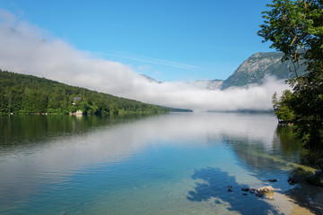Lake Bohinj and surrounding mountains in fog on a summer morning