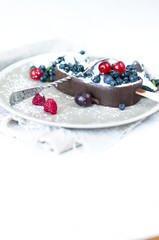Melting ice cream with chocolate glaze and garnished with fresh berries.