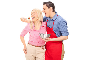 Young man in a red apron feeding his girlfriend