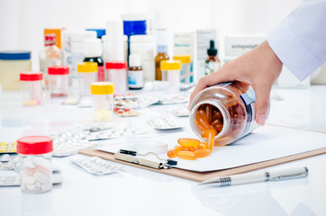 pharmacist hand holding medicine container on a folder