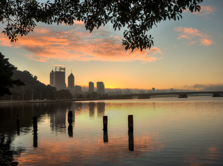 Fototapeta na wymiar Dawn, City of Perth, Western Australia, with fog and orange clouds reflected in the Swan River