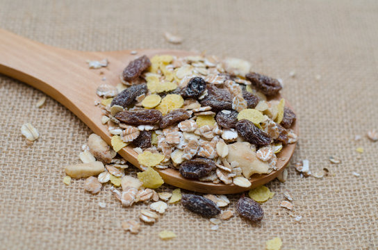 Oat flakes in wooden spoon on sackcloth background