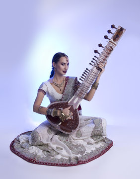 Beautiful Indian Woman in Sari with Oriental Jewelry Playing the