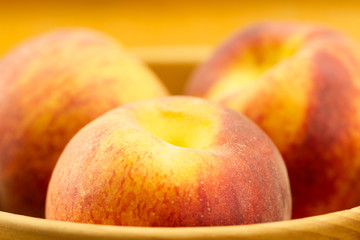ripe fresh peaches on a plate on wooden background