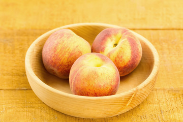 ripe fresh peaches on a plate on wooden background