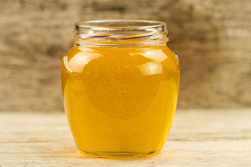 glass jar of fresh honey on wooden background