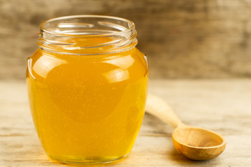 glass flower honey jar with spoon on wooden background