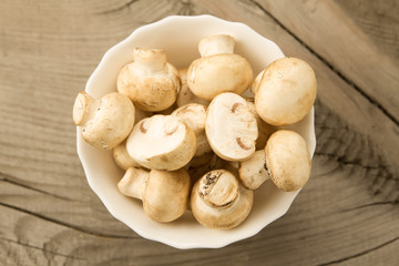 fresh mushrooms on a plate on wooden background, top view