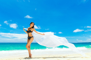 Fototapeta na wymiar Young beautiful girl in bikini with white cloth on the beach of