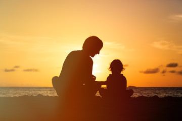 Silhouette of father and little daughter at sunset