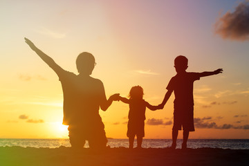 Fototapeta na wymiar father with two kids at sunset beach