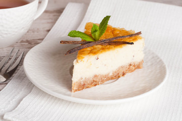 Vanilla cheesecake on a white plate and cup of tea, close up