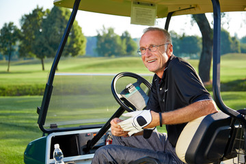 Senior golfer sitting in a golfcart and smile