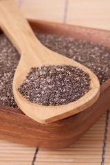 Chia Seeds on a Spoon – Chia seeds on a spoon. Chia seeds in a wooden bowl in the background.