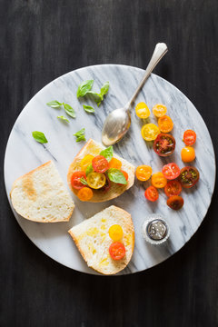 Bruschetta with a Mix of Red, Orange and Yellow Cherry Tomatoes and Basil Leaves