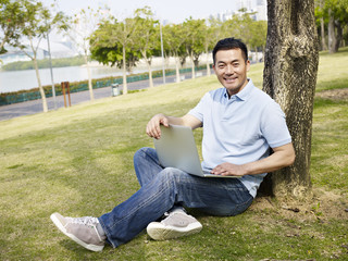 asian man using laptop outdoors