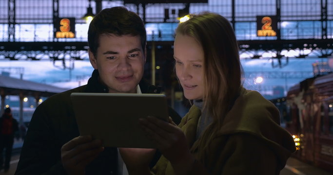Young people using pad at station in the evening