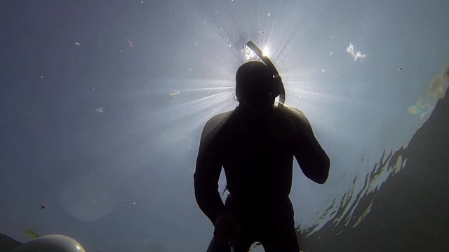 freediver taucht durch zwei roehren im see
