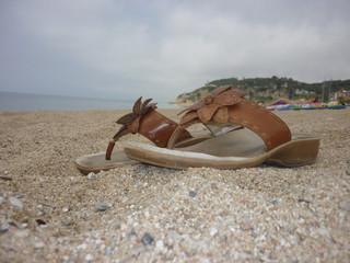 Leather flip flops on sandy beach