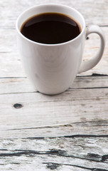 A mug of coffee drink over rustic weathered wooden background