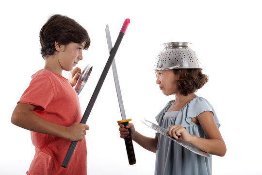 Ni&ntilde;o y ni&ntilde;a jugando a guerreros con enseres de cocina