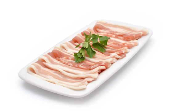 Slices of bacon with parsley on the plate isolated on white