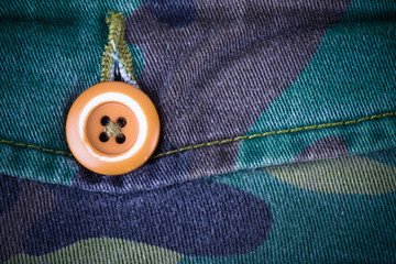 Pocket with a button on the fabric with a camouflage pattern. Ba