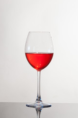 Calice di vino, su piano riflettente e sfondo bianco