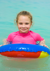 Smiling little girl with a floating ring at a tropical beach