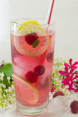 Raspberry ice tea with lemon raspberry and ice cubes on a table
