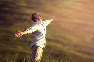 A man stands with his arms outstretched in an open field..