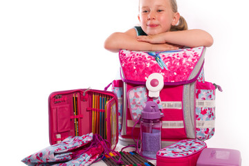l&auml;chelnd pr&auml;sentiert ein Kind zur Einschulung die neuen Schulsachen 