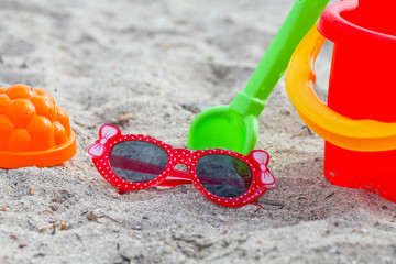 Child red sunglasses lie on a beach