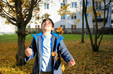 Happy boy throwing autumn leaves.