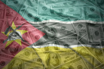 colorful waving mozambican flag on a american dollar money background