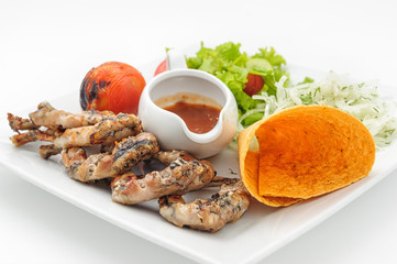 Grilled frogs with crisp loaf and spicy sauce isolated on white.