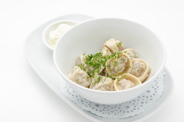 Russian traditional dish ravioli with sour cream isolated on white.