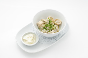 Russian traditional dish ravioli with sour cream isolated on white.
