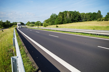 Empty asphalt expressway with white truck arriving from afar in the countryside