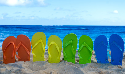 Fototapeta premium Colorful flip flops on the sandy beach