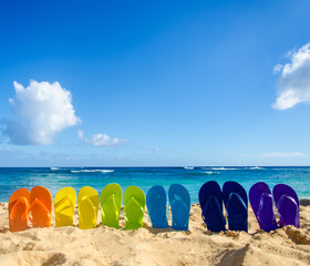 Obraz premium Colorful flip flops on the sandy beach