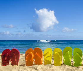Obraz premium Colorful flip flops on the sandy beach