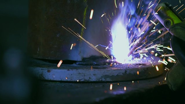 Close-up of metal being welded at workshop. Detail of sparks coming out from welding torch.
