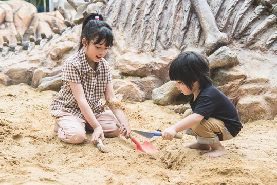 Little asian children has fun digging in the sand