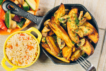 A pan of baked potatos with a bowl of rice and vegetables