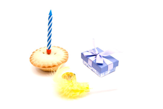 Cupcake with blue birthday candle, whistle and gift