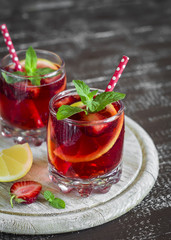 strawberry lemonade with lemon and mint in glass beakers on a light surface